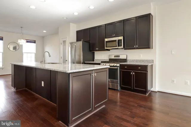 a kitchen with stainless steel appliances granite countertop a stove a sink dishwasher a refrigerator and a microwave oven with wooden floor