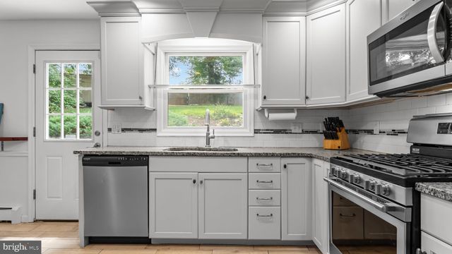 a kitchen with stainless steel appliances granite countertop a stove a sink and a microwave