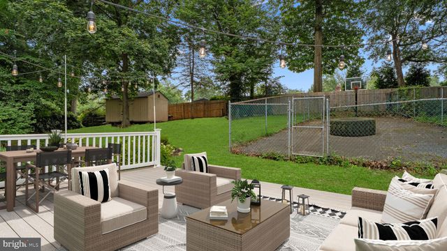a view of a backyard with large trees and wooden fence