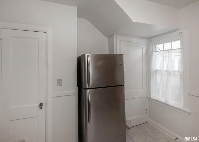 a view of a refrigerator in kitchen and white cabinets