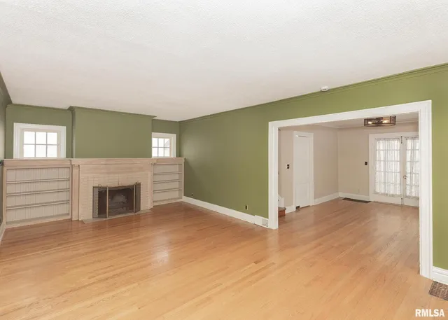 an empty room with windows and fireplace