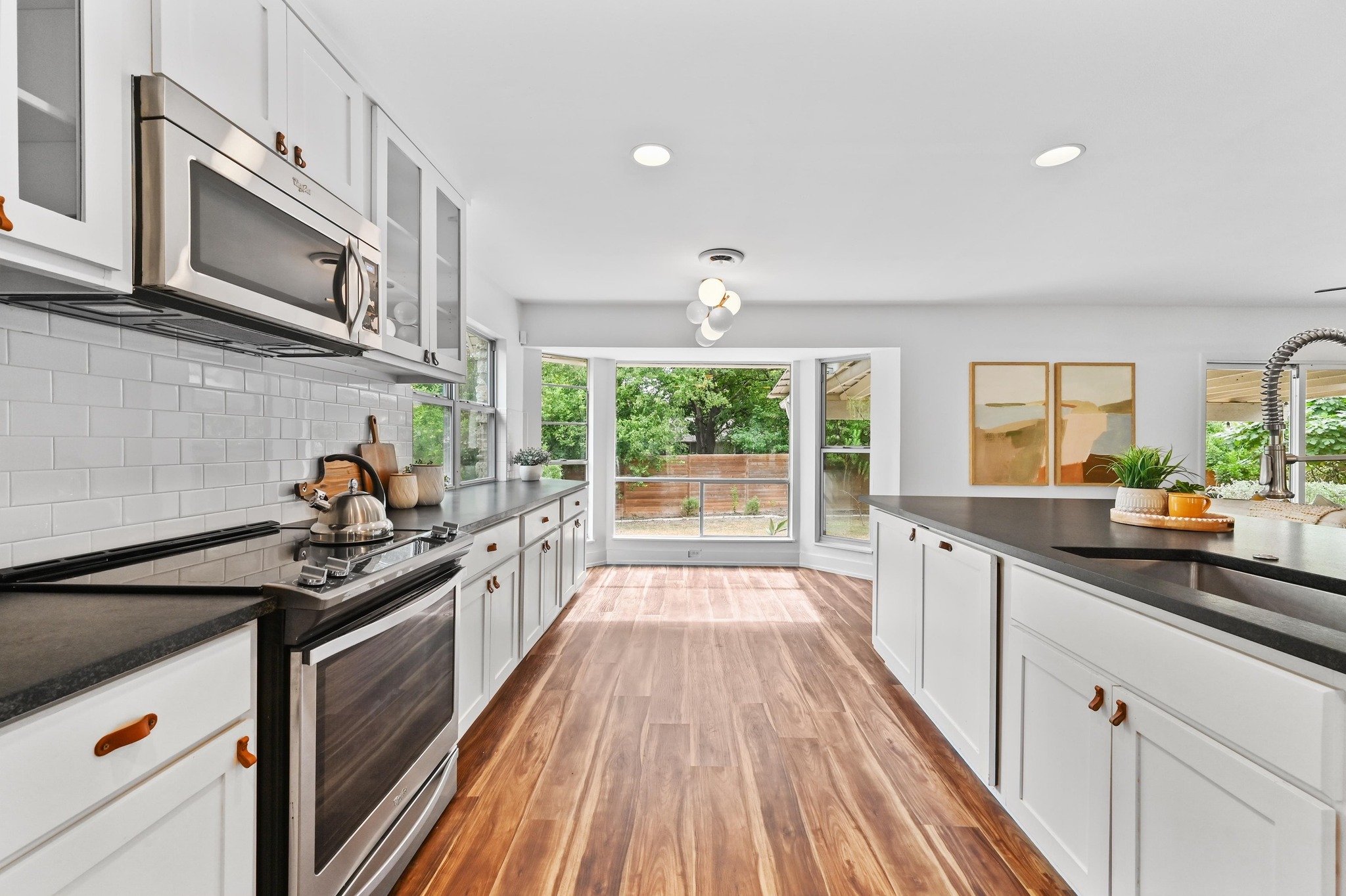 3405 Santa Fe Drive Austin, TX 78741 - Photo 13 of 23 Kitchen with appliances with stainless steel finishes, white cabinets, recessed lighting, light wood-style floors, and tasteful backsplash