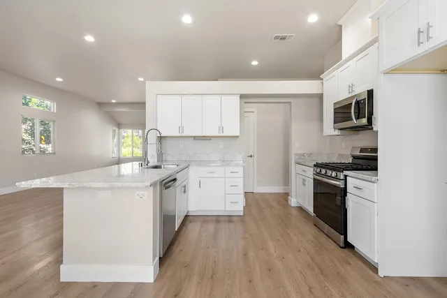 a kitchen with stainless steel appliances kitchen island granite countertop a stove a sink and a refrigerator