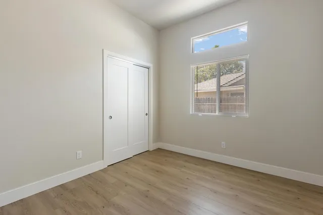 an empty room with wooden floor and windows