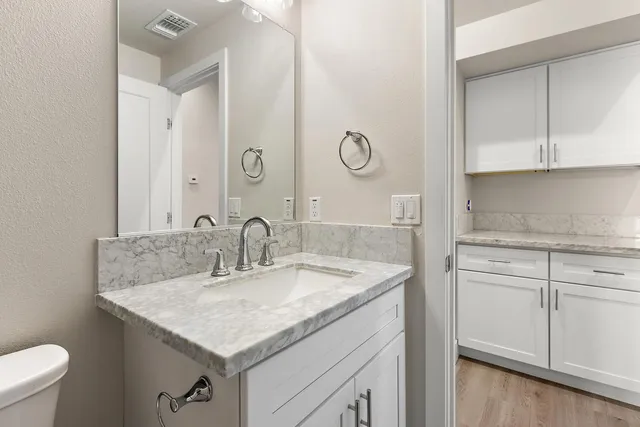 a bathroom with a granite countertop sink a toilet and a mirror
