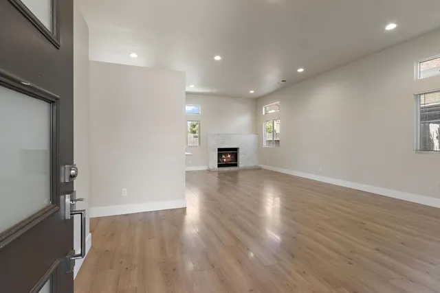 an empty room with wooden floor and windows