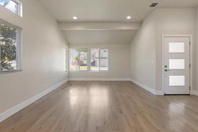 an empty room with wooden floor and windows