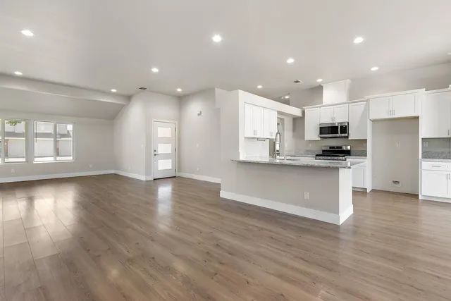 a view of kitchen with granite countertop stainless steel appliances refrigerator sink and cabinets