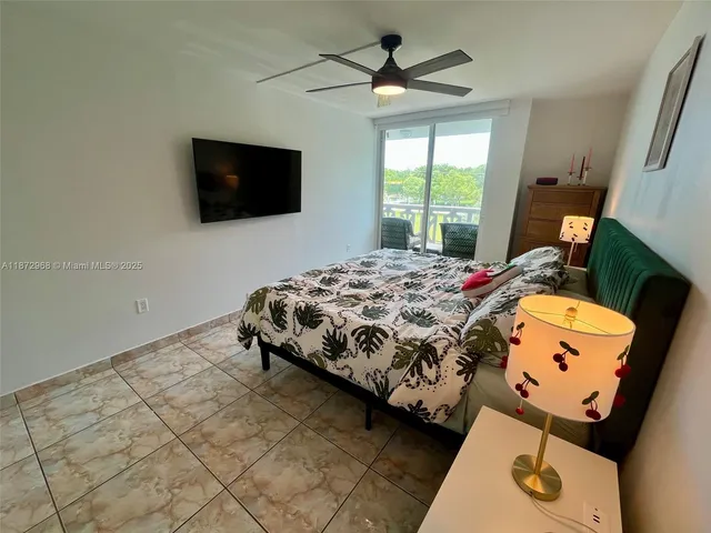 a bedroom with a bed a window and a flat screen tv