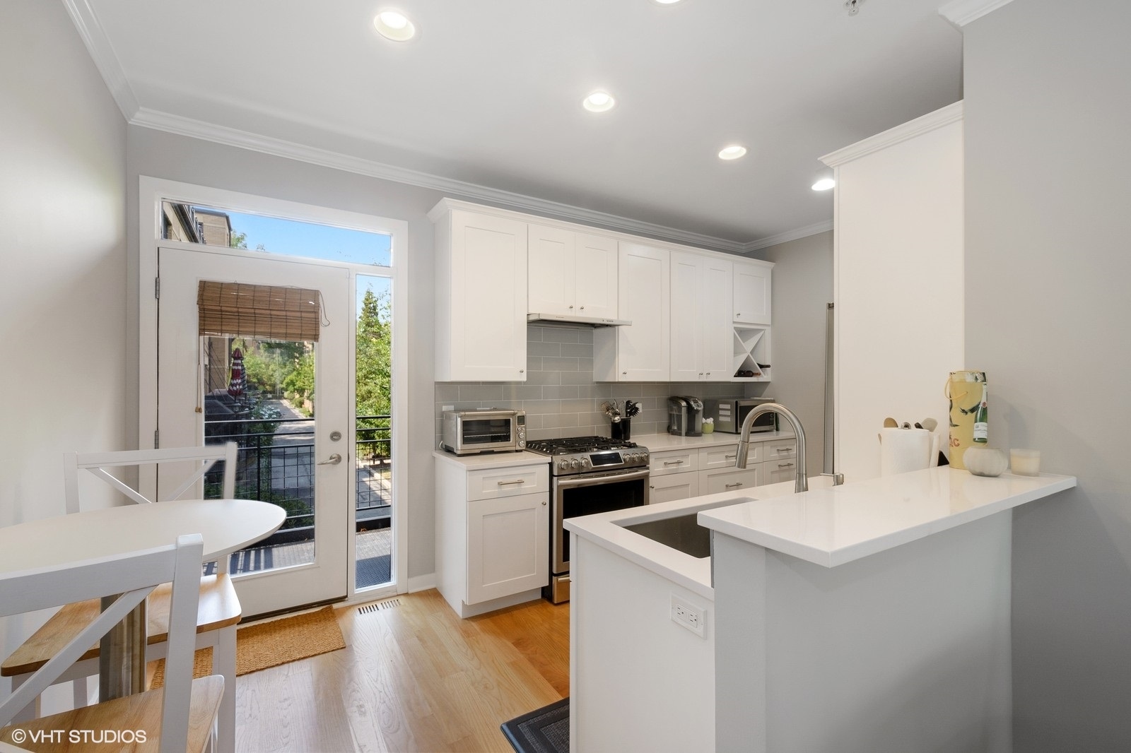 1244 West Monroe Street, Unit 4 Chicago, IL 60607 - Photo 7 of 16 a kitchen with a sink a stove a refrigerator and white cabinets with wooden floor