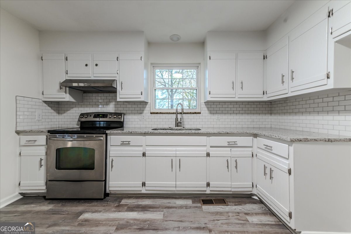 111 Collins Street Byron, GA 31008 - Photo 3 of 26 a kitchen with granite countertop white cabinets and stainless steel appliances