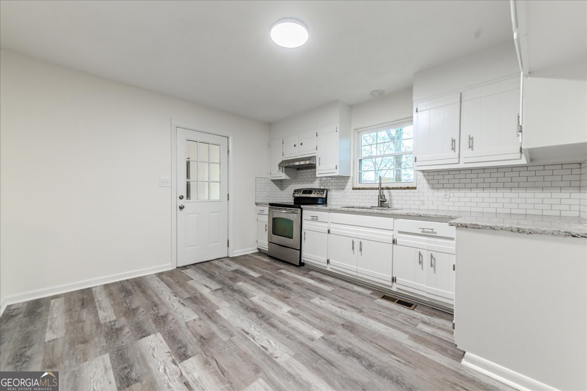 111 Collins Street Byron, GA 31008 - Photo 4 of 26 a kitchen with granite countertop white cabinets and white appliances