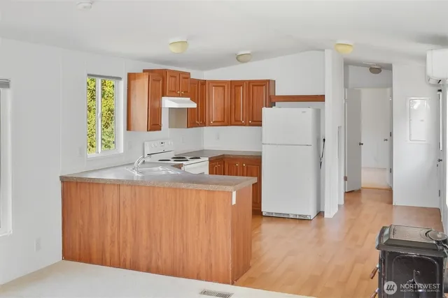 a kitchen with a refrigerator a stove a sink dishwasher and a dining table with wooden floor