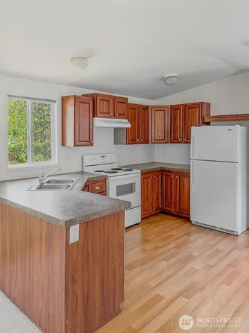 a kitchen with stainless steel appliances granite countertop a stove a sink dishwasher and a refrigerator with wooden floor