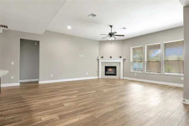 a view of an empty room with wooden floor and a fireplace
