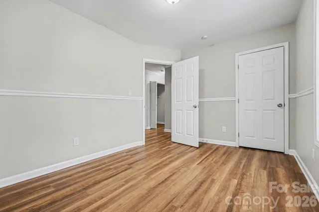 a view of an empty room with wooden floor and closet