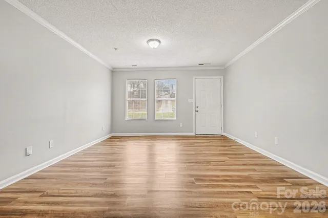 a view of an empty room with wooden floor and window