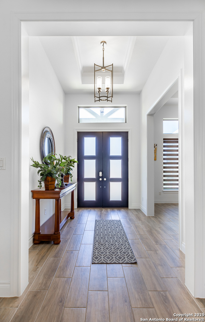 34784 High Gate Road Bulverde, TX 78163 - Photo 2 of 34 a view of a hallway with wooden floor and a chandelier