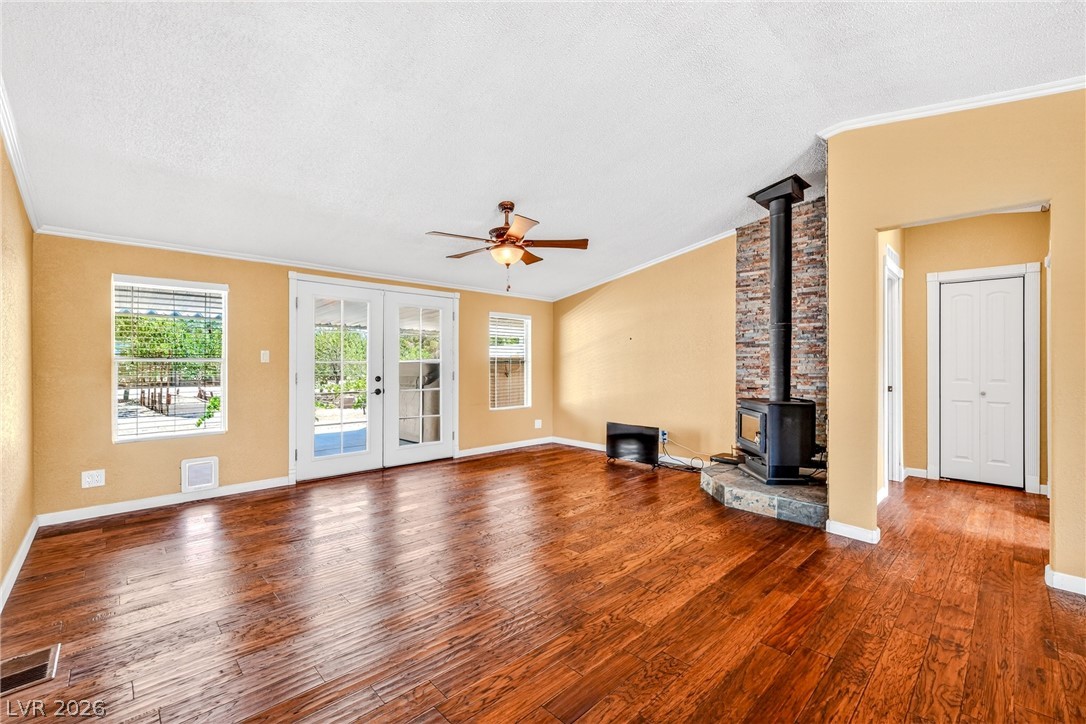1831 West Horn Road Pahrump, NV 89048 - Photo 10 of 59 Hardwood floors stretch across this inviting living space, featuring French doors that open to the outdoors and a cozy wood-burning stove.