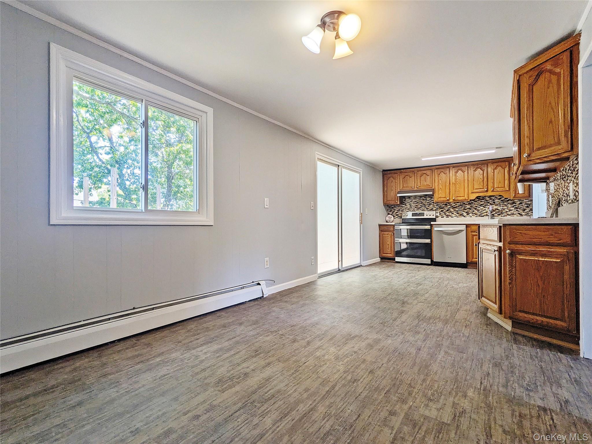 17 Belair Road Selden, NY 11784 - Photo 4 of 18 Wood-finish flooring, kitchen with wood cabinetry and stainless steel appliances, tile backsplash, and sliding glass doors