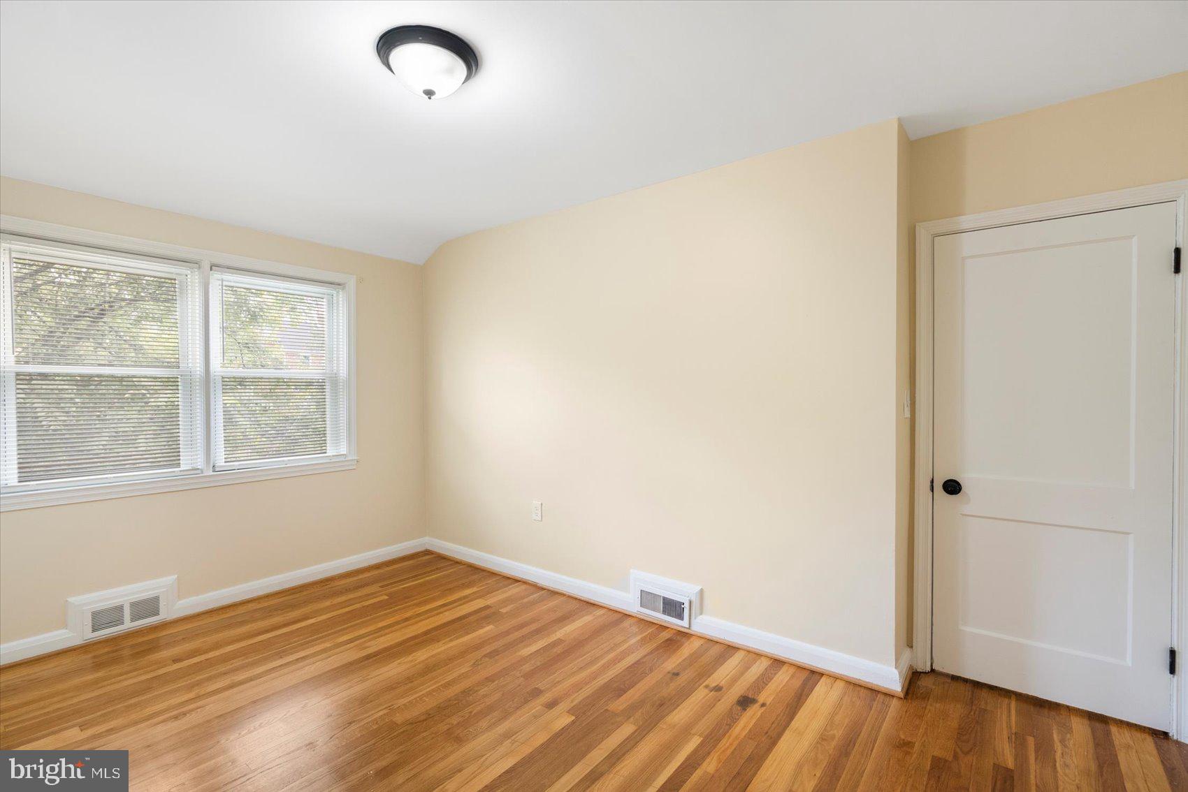 1444 Meridene Drive Baltimore, MD 21239 - Photo 22 of 36 an empty room with wooden floor and windows