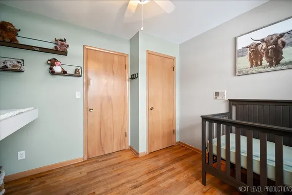 a view of hallway with wooden floor and fan