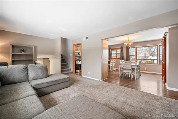 a living room with furniture and a dining table with floor to ceiling window