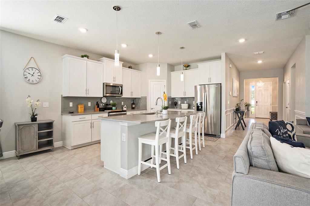 10903 Honor Road Tampa, FL 33625 - Photo 14 of 36 a kitchen with stainless steel appliances kitchen island granite countertop a refrigerator a stove a sink a dining table and chairs with wooden floor