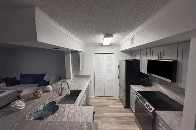 a kitchen with stainless steel appliances kitchen island granite countertop a refrigerator stove and sink