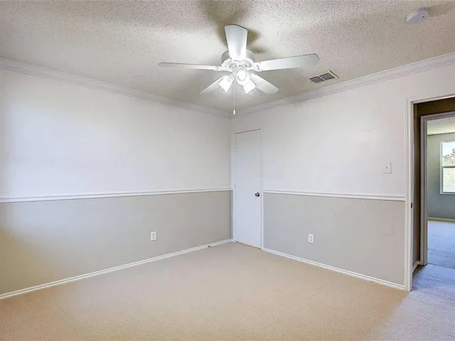 an empty room with a chandelier fan and closet