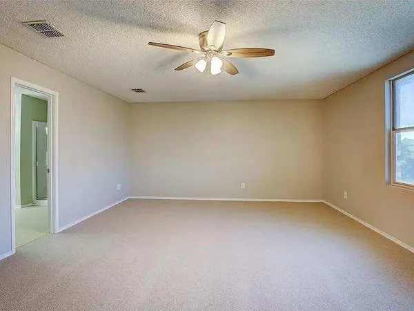 an empty room with a window and a ceiling fan