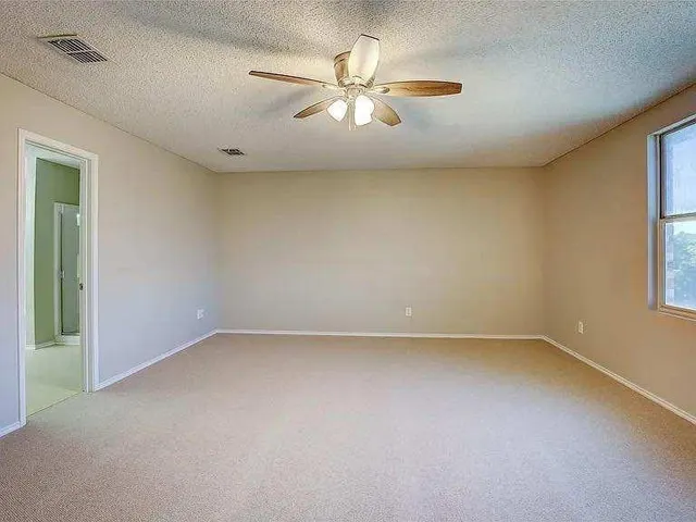an empty room with a window and a ceiling fan