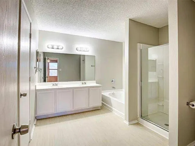 a bathroom with a tub shower sink and mirror