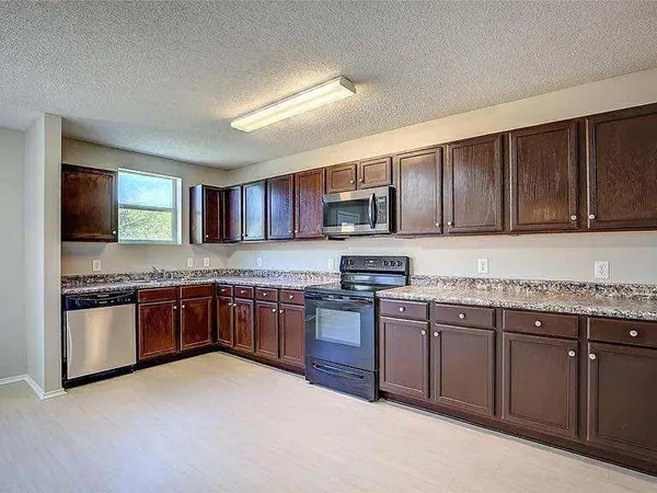 a kitchen with stainless steel appliances granite countertop wooden cabinets a stove top oven a sink and dishwasher