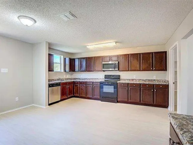 a large kitchen with stainless steel appliances granite countertop a stove and cabinets