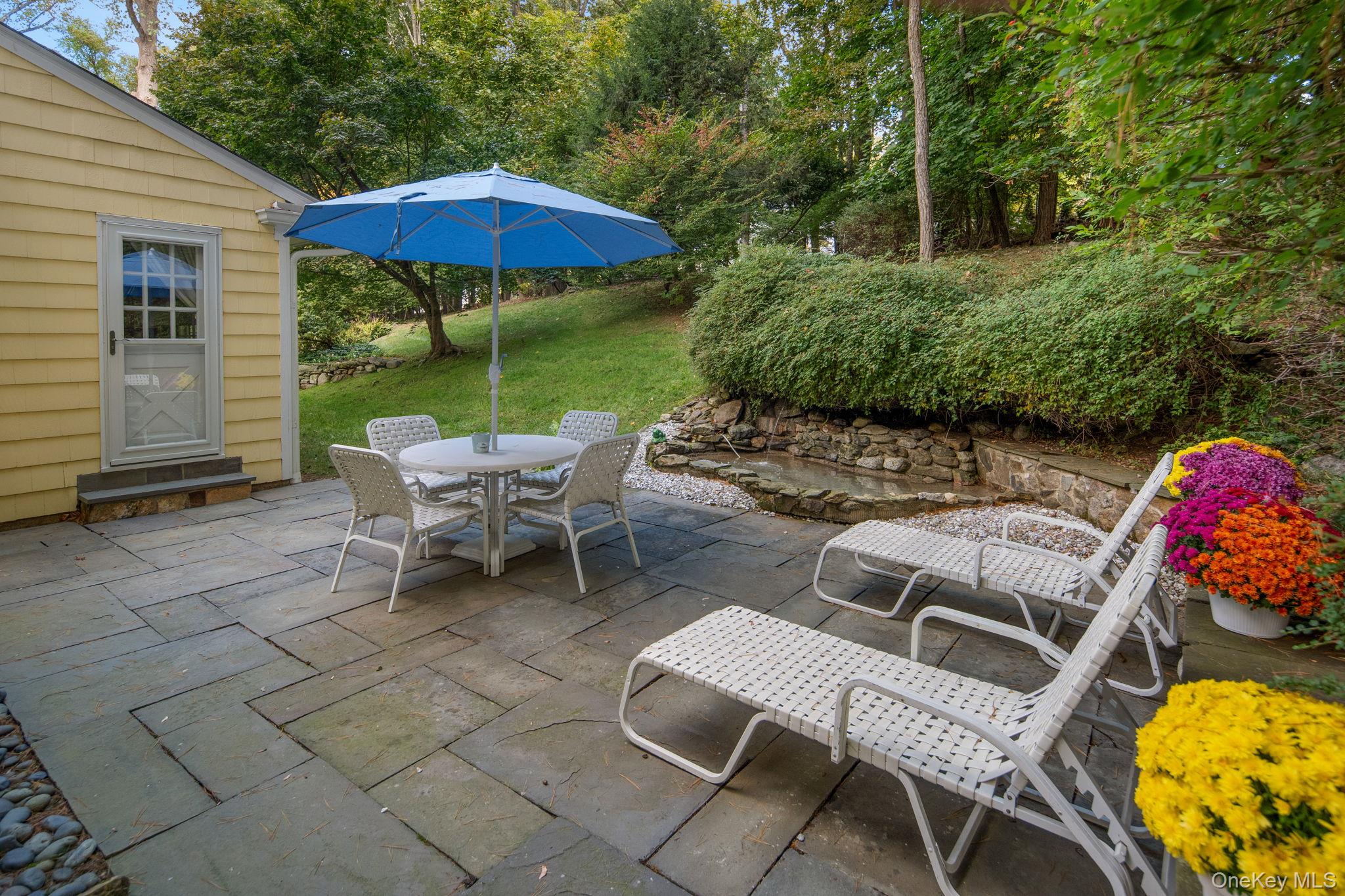 111 Seven Bridges Road Chappaqua, NY 10514 - Photo 5 of 29 a view of a patio with a table and chairs under an umbrella