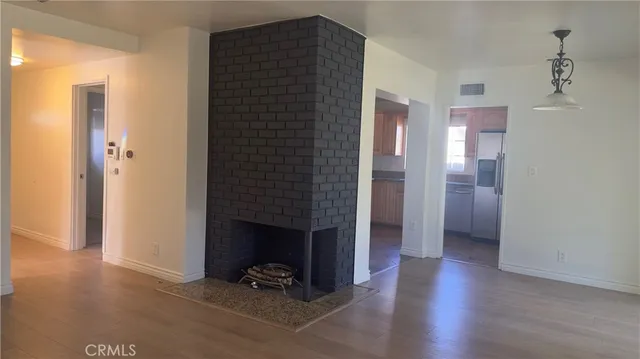 a view of an empty room with wooden floor and a fireplace