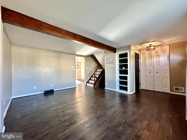 a view of an empty room with wooden floor stairs and a window