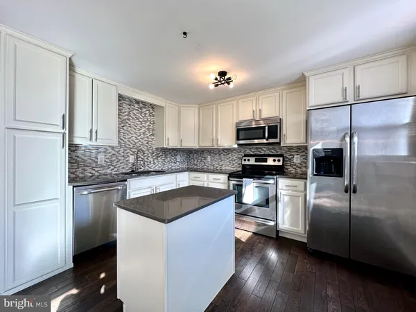 a kitchen with granite countertop a refrigerator stove and microwave