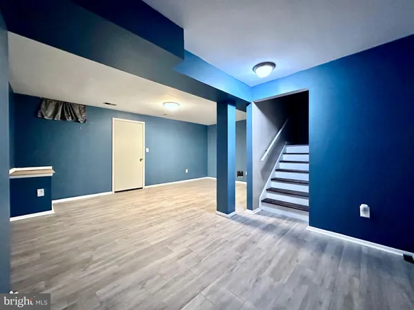 a view of an empty room with wooden floor and stairs