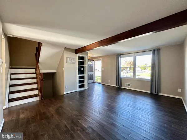 an empty room with wooden floor closet and windows