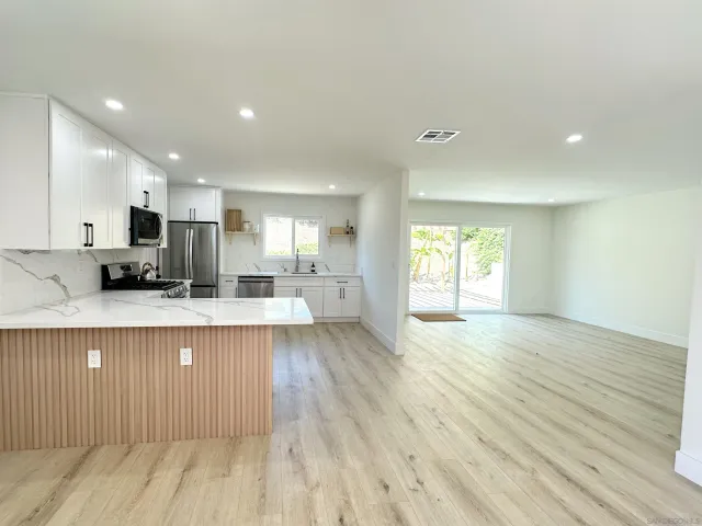 a large kitchen with stainless steel appliances a large window a sink and a refrigerator