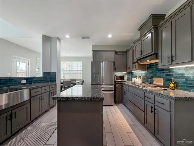 a kitchen with stainless steel appliances granite countertop sink stove refrigerator and cabinets