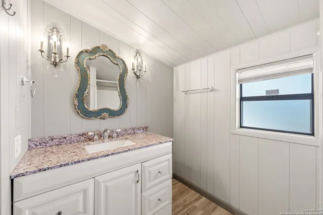 a bathroom with a granite countertop sink a mirror and a vanity