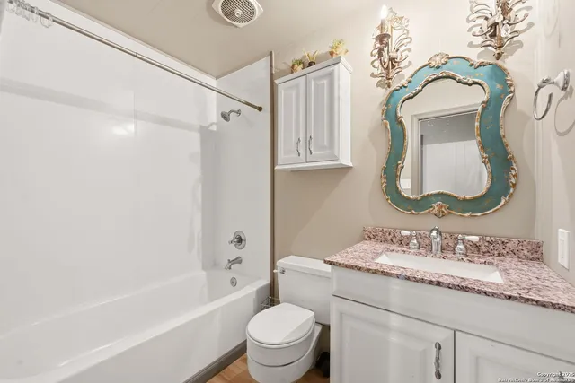 a bathroom with a granite countertop sink mirror toilet and bathtub