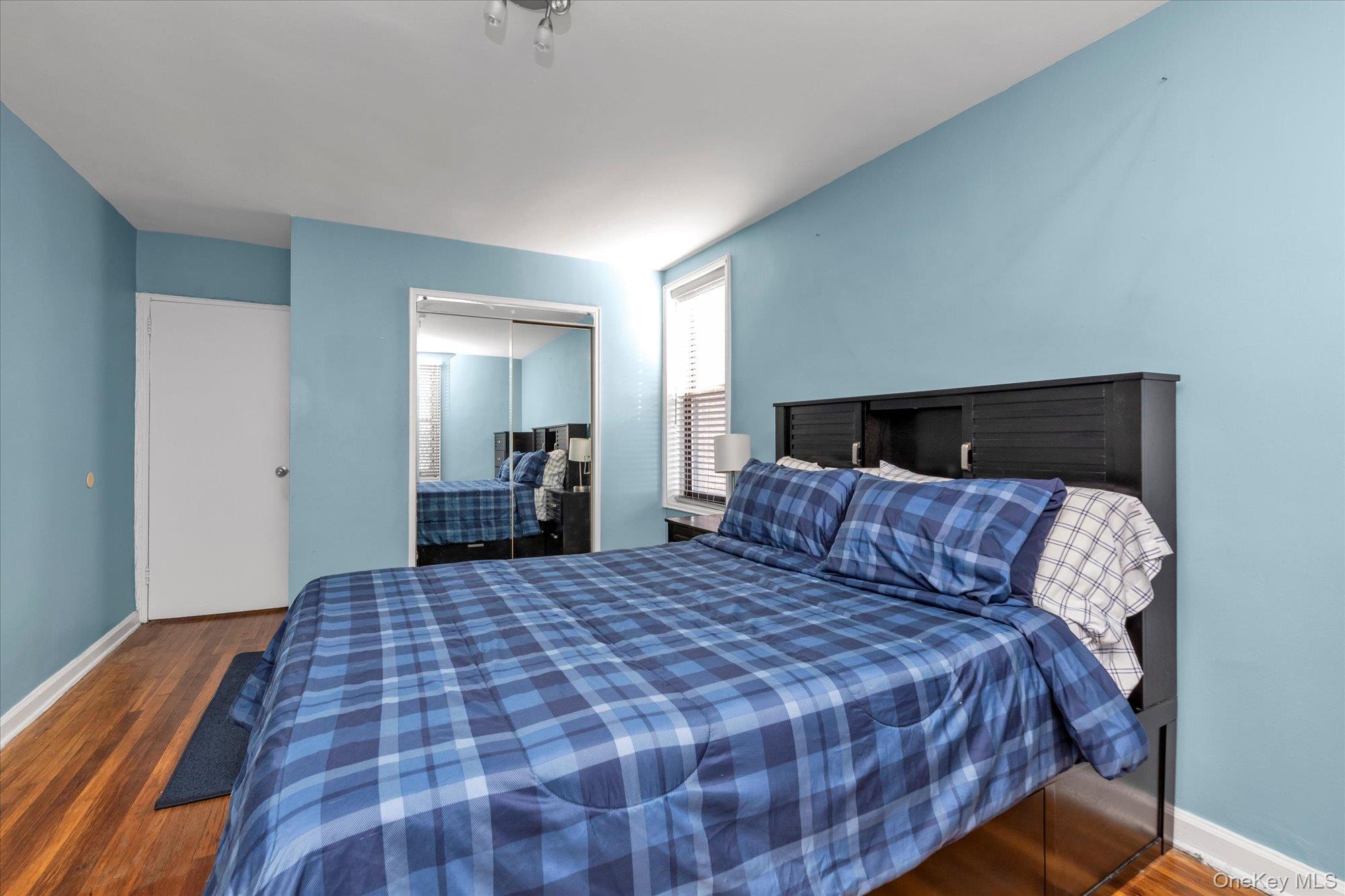 83-40 Austin Street, Unit 7K Queens, NY 11415 - Photo 11 of 19 a large bed sitting in a bedroom and a mirror