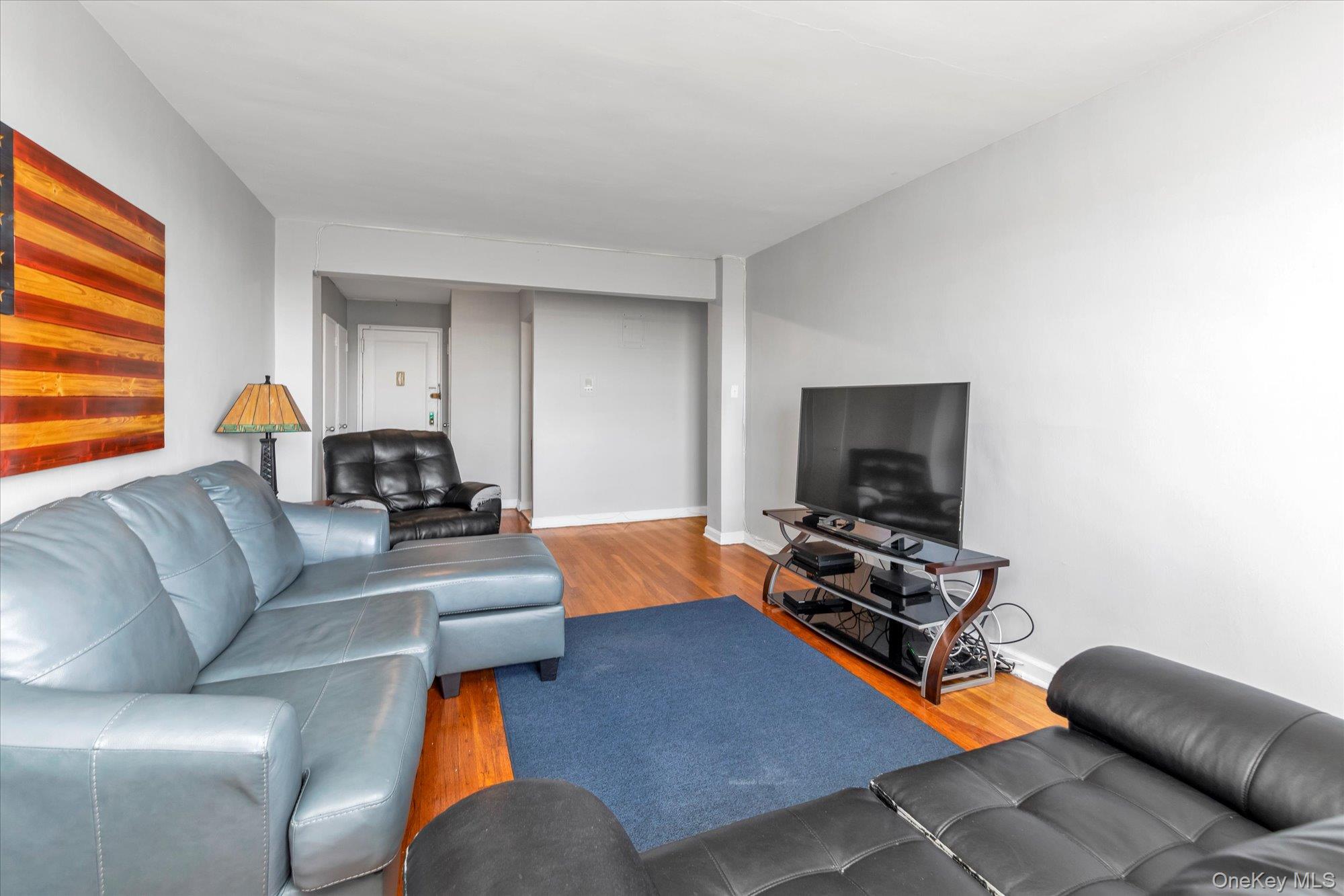 83-40 Austin Street, Unit 7K Queens, NY 11415 - Photo 5 of 19 a living room with furniture and a flat screen tv