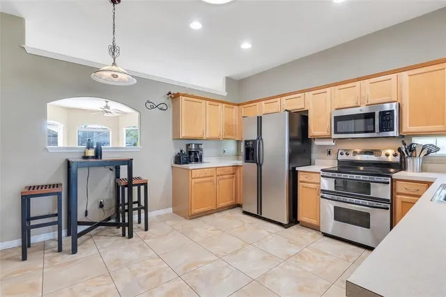 a kitchen with granite countertop a refrigerator a stove top oven a sink dishwasher a dining table and chairs with wooden floor