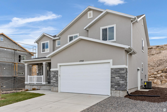 387 Slant Road, Unit 30 Spanish Fork, UT 84660 - Photo 2 of 25 Contemporary two-story residence featuring a two-car garage, stone and stucco facade, covered porch with white railings, and a concrete driveway