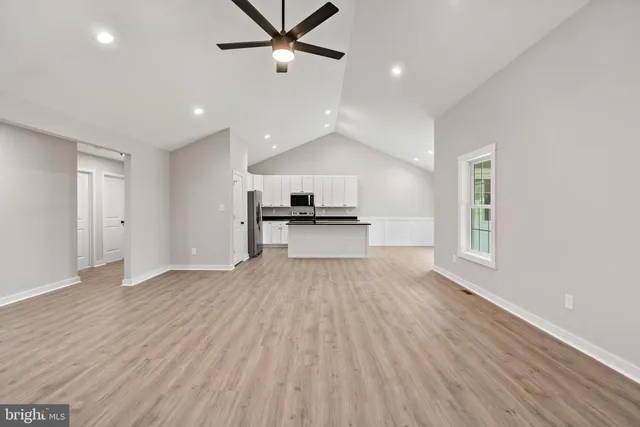 a view of empty room with wooden floor and ceiling fan